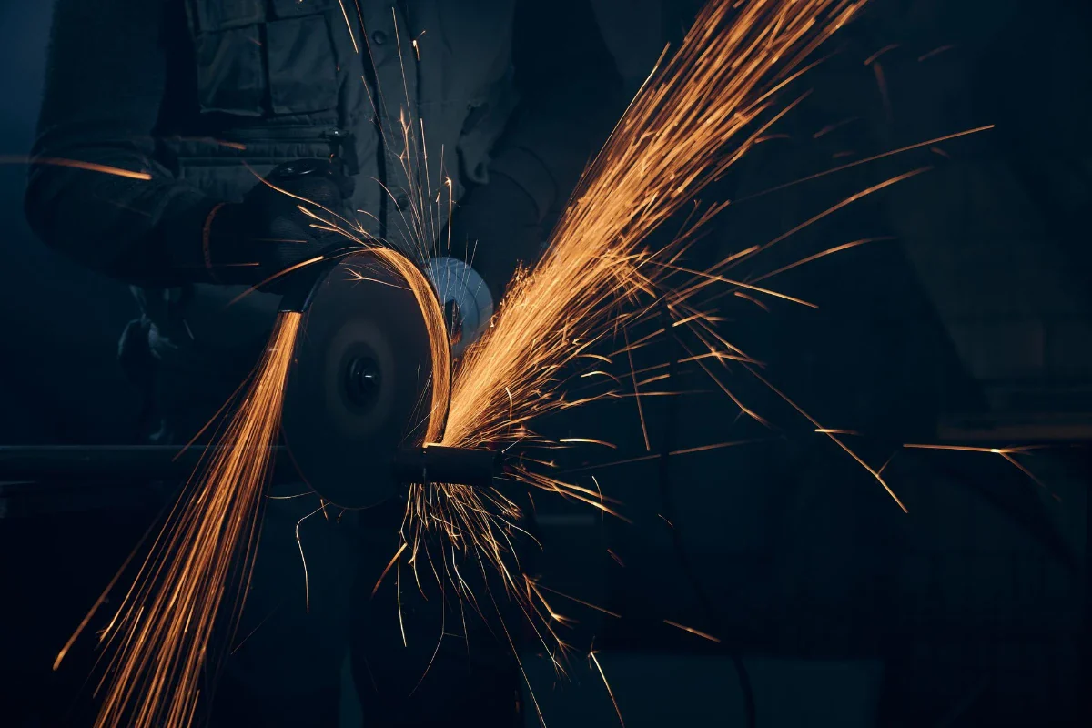 Worker grinding a metal component in an industrial workshop